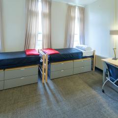 A bedroom with two twin beds, dressers, tables, and chair.