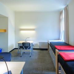 A bedroom with two twin beds, dressers, tables, and chair.