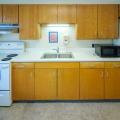 A communal kitchen with a table, chairs, fridge, microwave, sink, stove, oven, countertops and cabinets