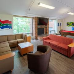 A large lounge with couches, chairs, tables, a pool table, and tv.