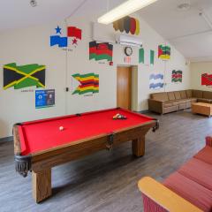 A large lounge with couches, chairs, tables, a pool table, and tv.