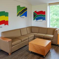One wall of the lounge with a couch, table, and flags of different countries painted on the wall.