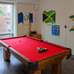 A large lounge with couches, chairs, tables, a pool table, and tv.