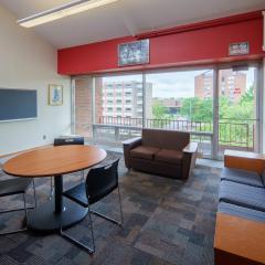 A small lounge with couches, chairs, tables, and a chalk board..