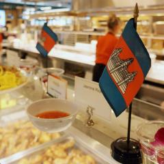 Cambodian flags sit on top of a food serving line with people in the background