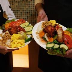 A closeup of two plates full of food being held by two people