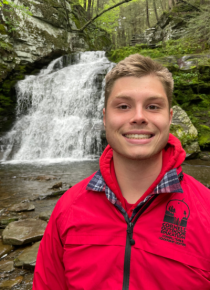 Trevor in red rain jacket near waterfall