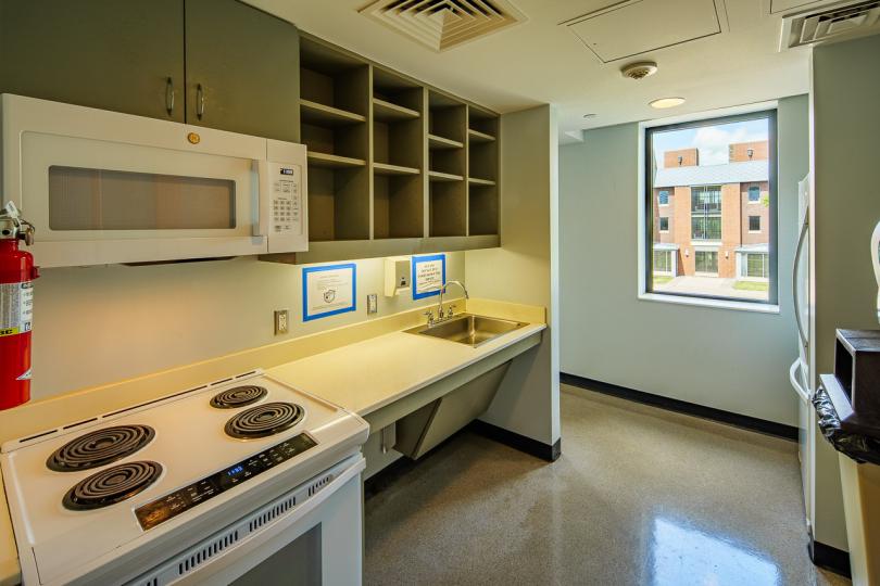 A small kitchen with cabinets and countertops, a sink, a fridge, a microwave, and a stove.