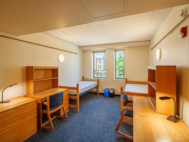 Double room in Mews Hall with two twin beds, desks, chairs, lamps, dressers, and a window.