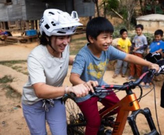 women in white helmet pushing kid on a bike