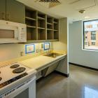 A small kitchen with cabinets and countertops, a sink, a fridge, a microwave, and a stove.