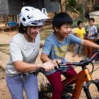 women in white helmet pushing kid on a bike