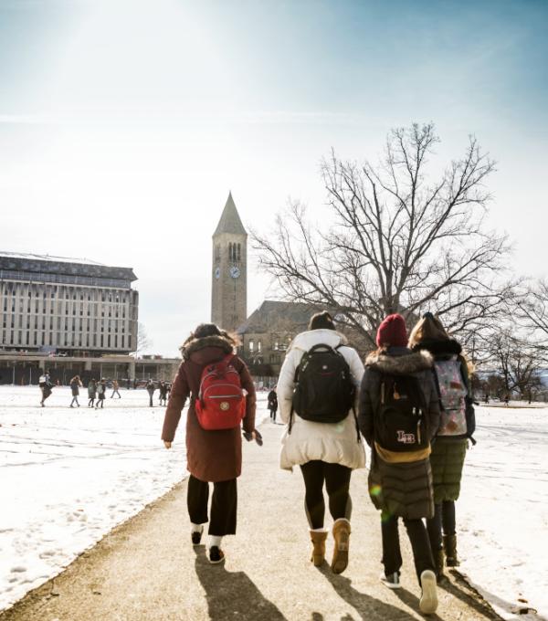Four students walk toward McGraw Tower on the Arts Quad