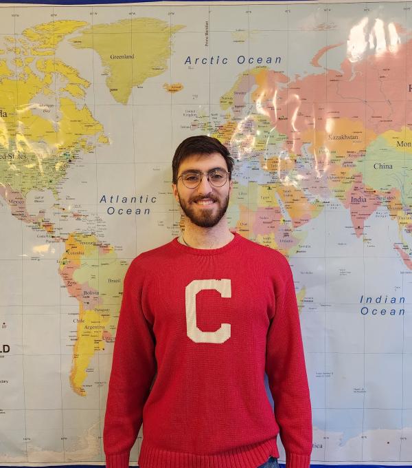 Armen Abrahamian smiling and standing in front of a global map