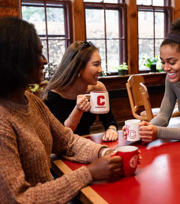 Smiling students around a table with coffee mugs