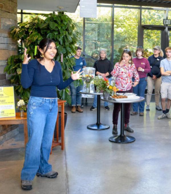 Shania Flores ’28, a student interpretation assistant with the botanic gardens, speaks in front of the Rooted in Reciprocity exhibit at an opening celebration Oct. 3.