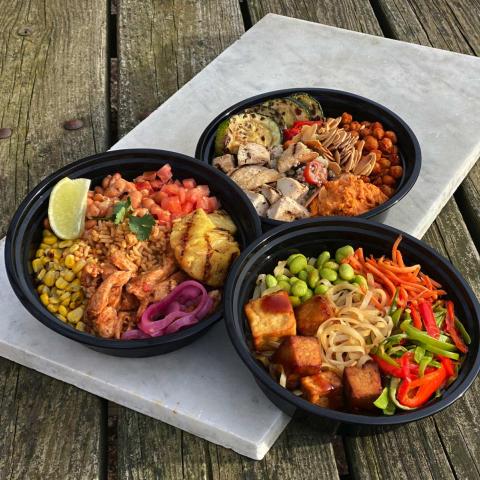 Three different food bowls on a marble tray atop a picnic table