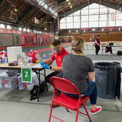 Student sits with medical professional to receive flu shot