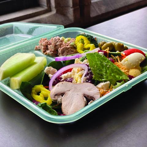 a reusable takeout container on a windowsill with food in it