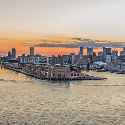 A view over water of a large building on a pier at dusk