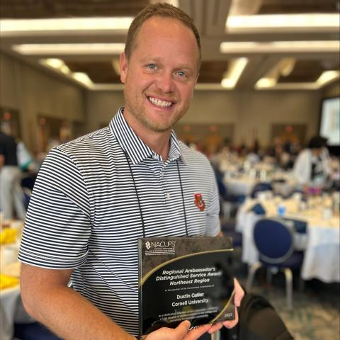 A smiling person holds an award plaque