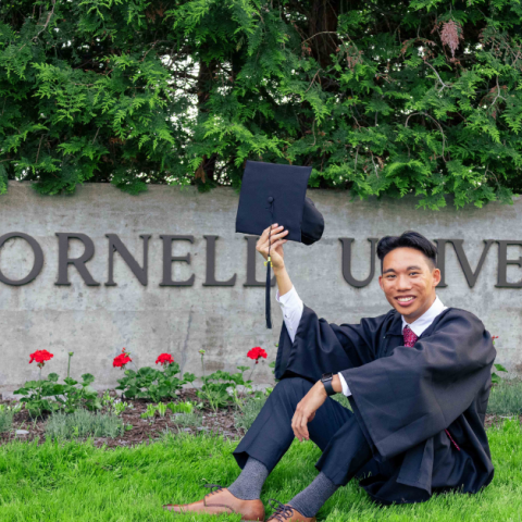 Justin as grad in front of Cornell University sign