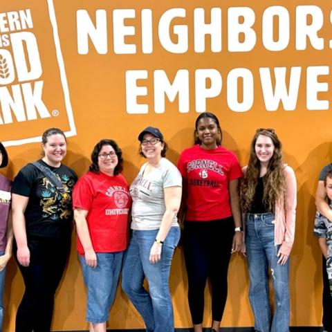 A group poses in front of a food bank sign