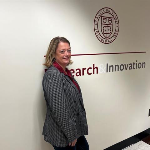 Photo of Lisa Rangel '92 in front of a wall at Cornell that says "Research and Innovation"