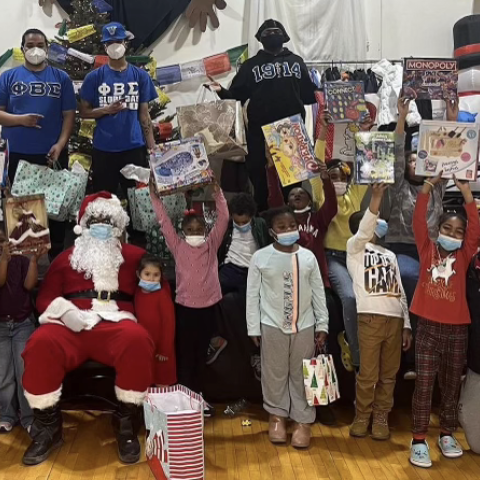 College students pose with children, gifts and Santa Claus