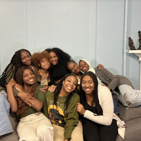 Wari residents smile together on a couch in their living room 