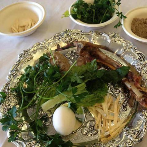 A seder plate with traditional Passover items on and around it