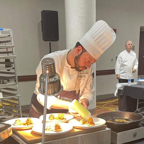 A chef prepares plates of food at a competition workstation