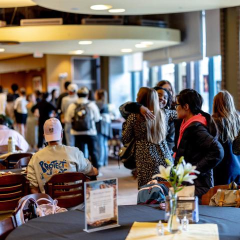 People seated at dining room tables and in line for food