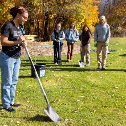 Gracekelly Fulton '24, co-lead of the Sustainable Landscapes team, prepares to plant a wild plum tree outside Onondaga Nation School.