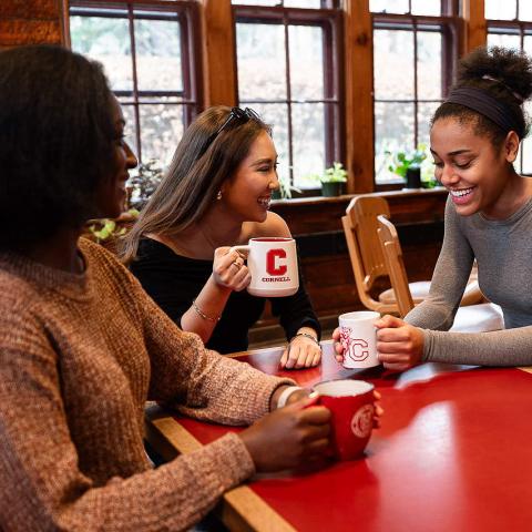 Smiling students around a table with coffee mugs