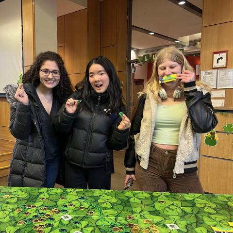 Three students behind a table decorated in green