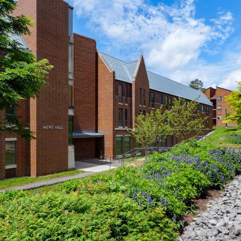 The entrance to Mews Hall with stairs to the walkway above, light posts, and landscaping