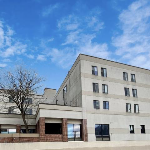 The exterior of a multi-story building with a bare tree in a courtyard in front