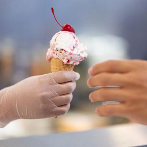 Food service worker handing ice cream cone to a customer