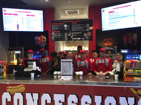 Group of concessions employees standing behind the service counter with menus above them.