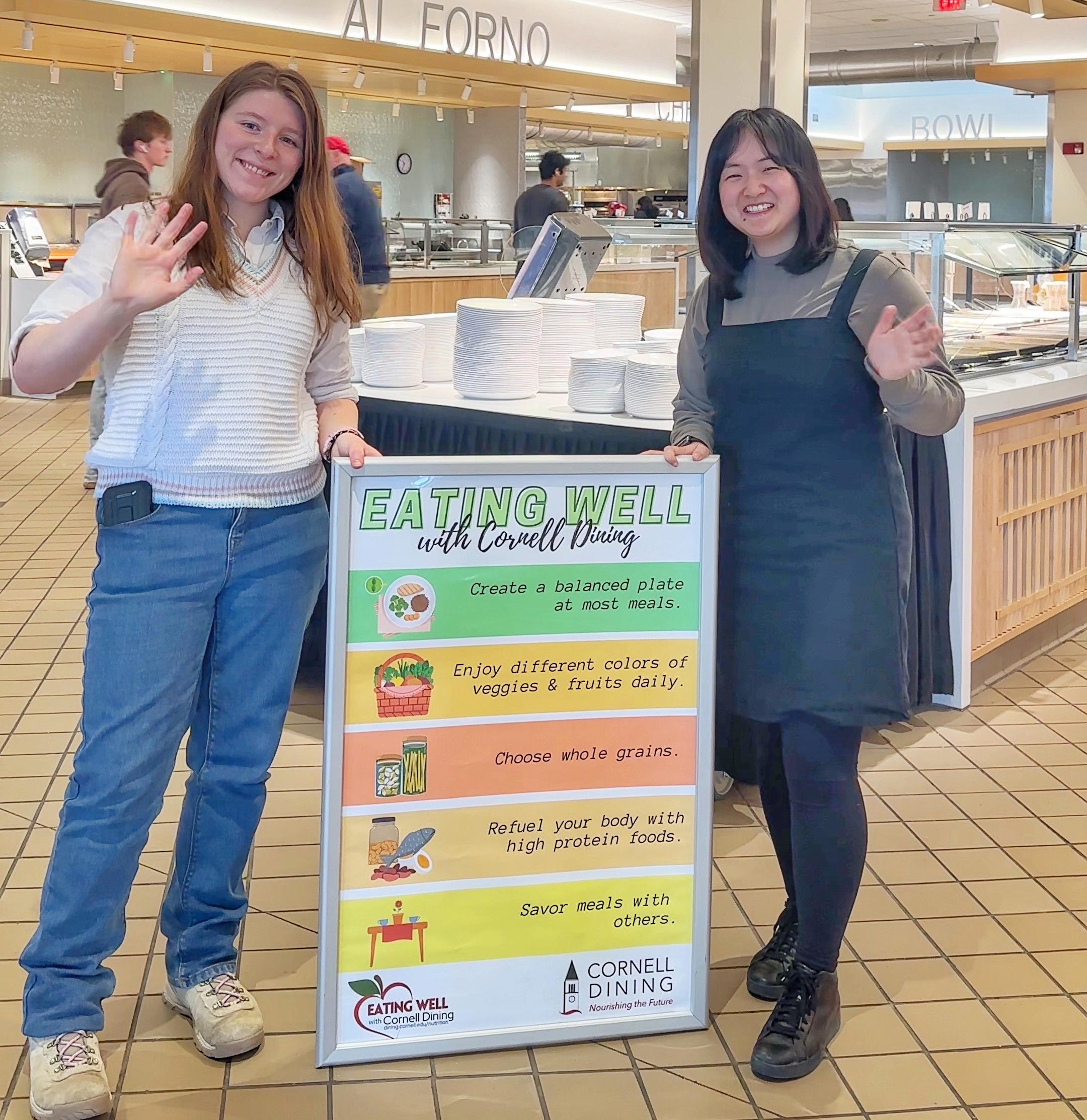 Students hold a sign that says Eating Well with Cornell Dining with a list of tips