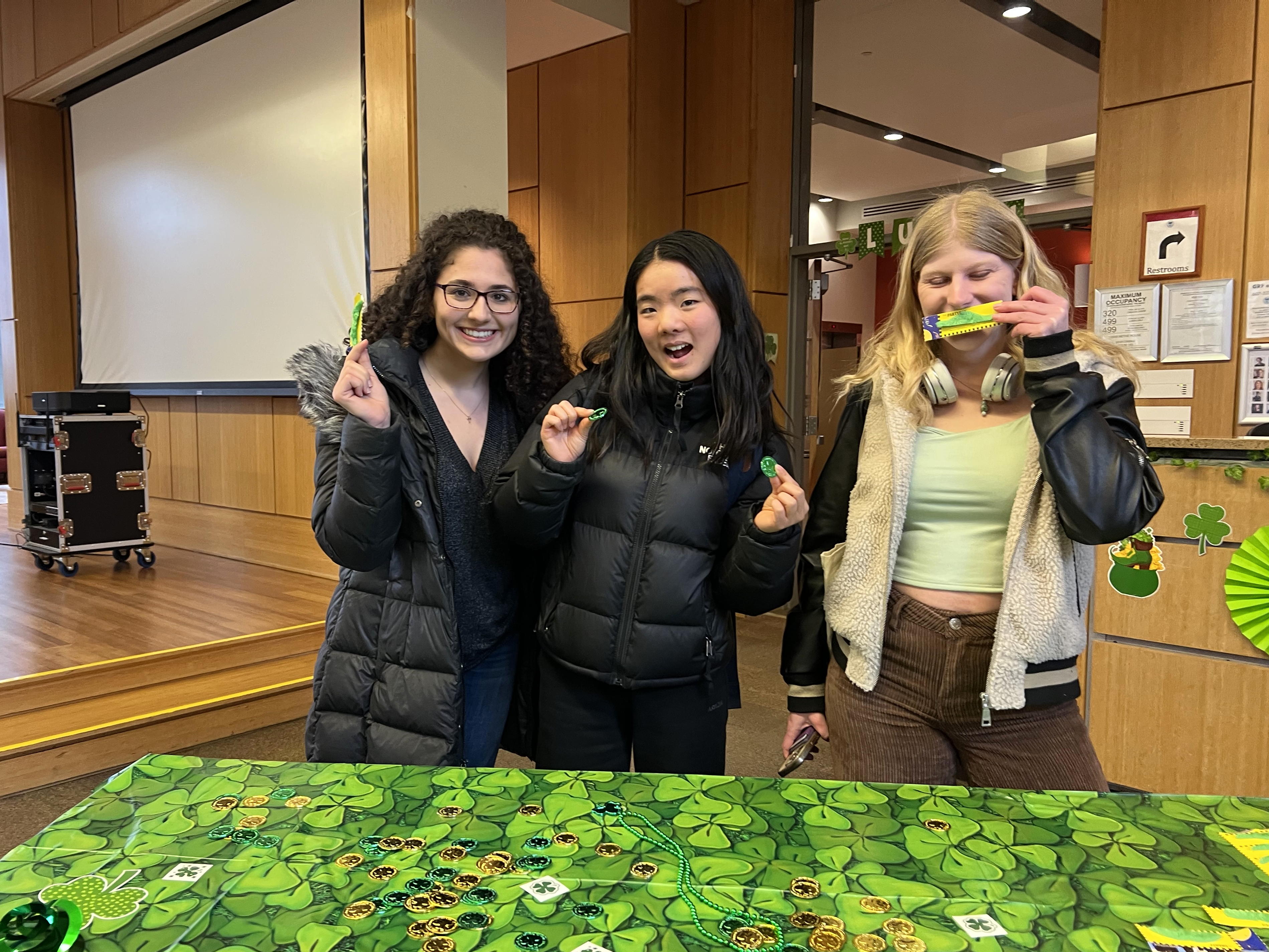 Three students behind a table decorated in green