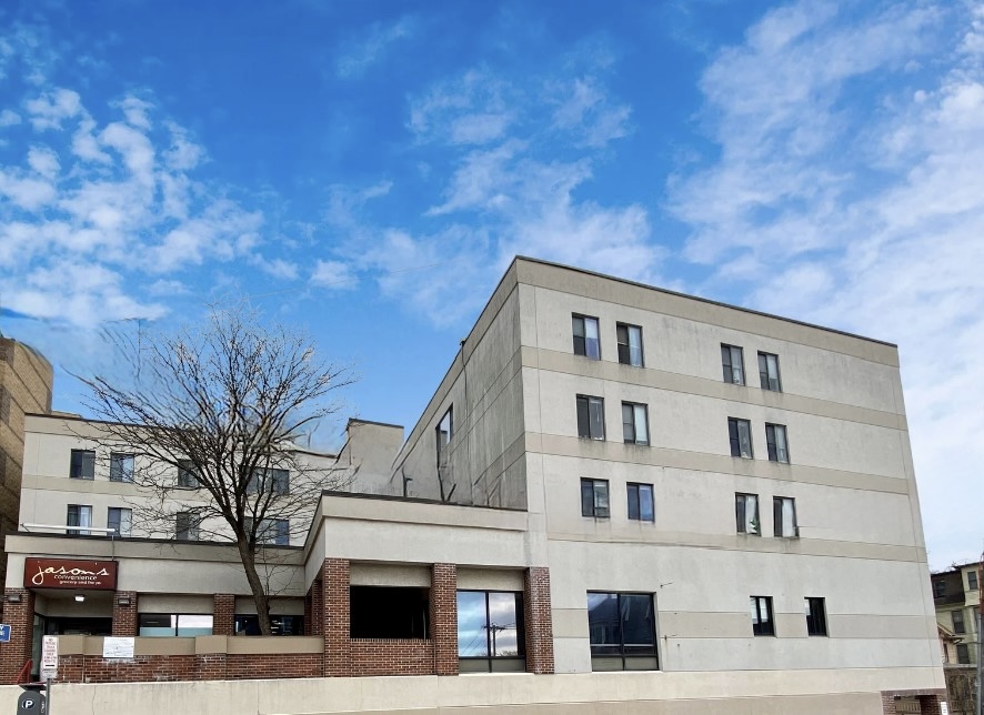 The exterior of a multi-story building with a bare tree in a courtyard in front