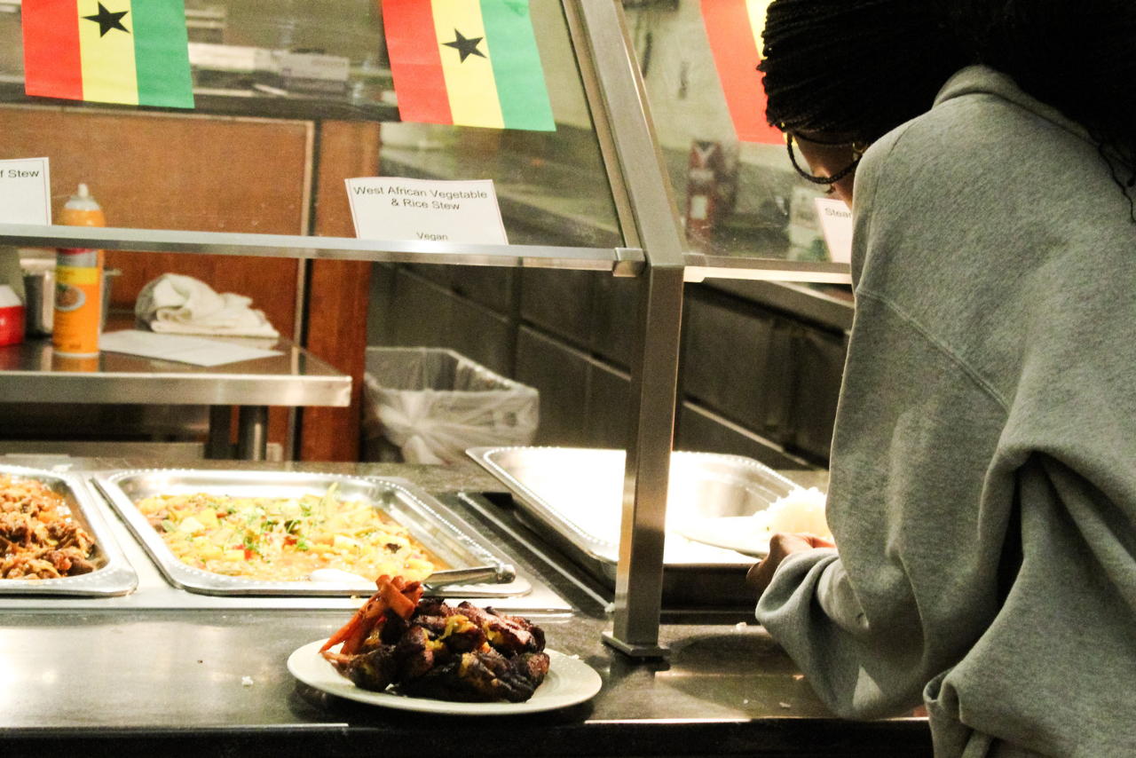 A student with a plate of food in front of a serving line