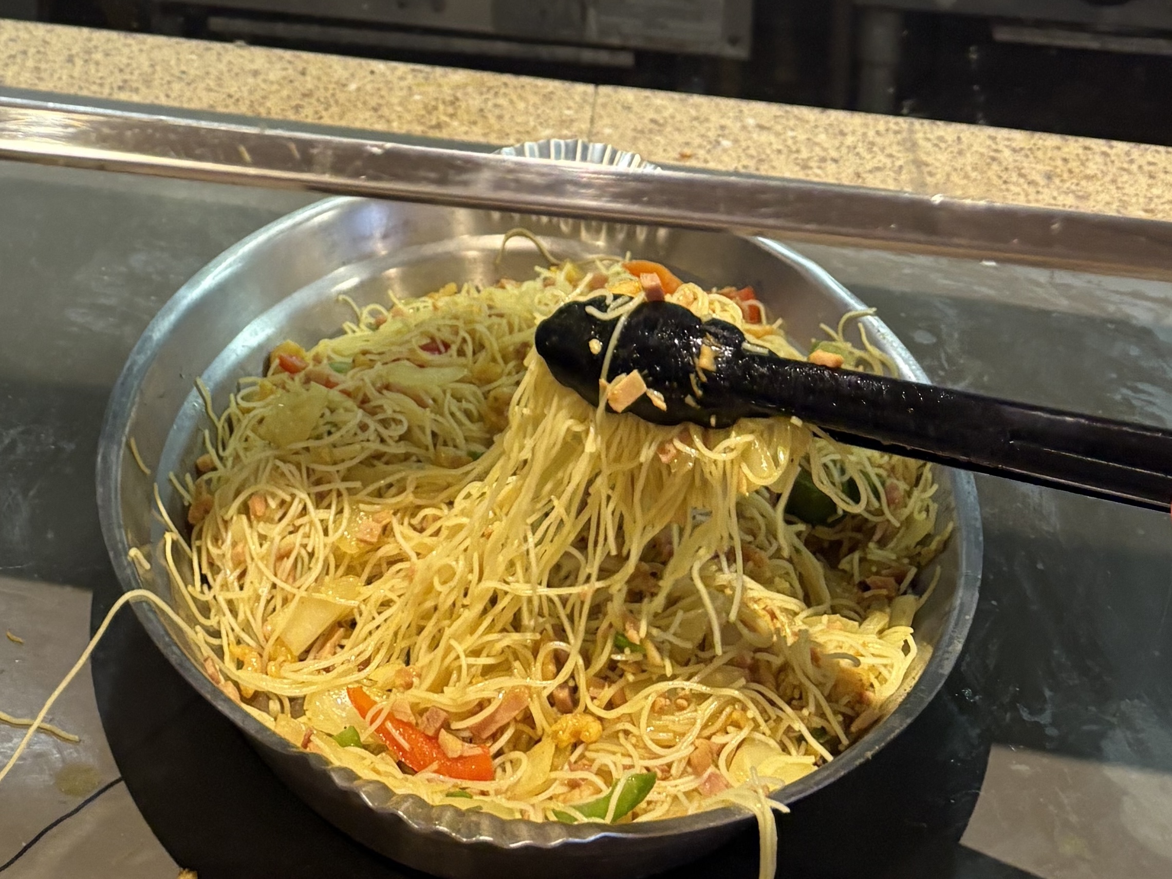 Tongs in a serving dish of noodles