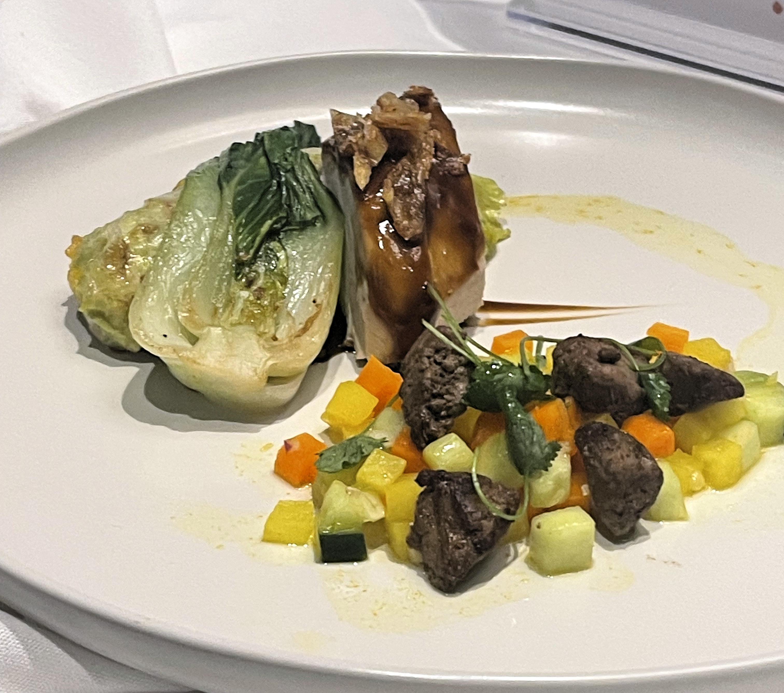 A plate of food including chunks of meat and vegetables, and grilled cabbage