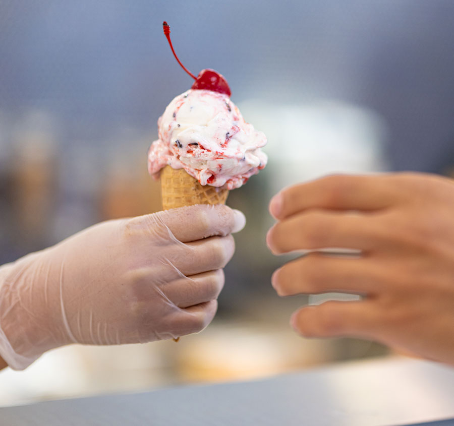 Ice cream cone being handed to a customer
