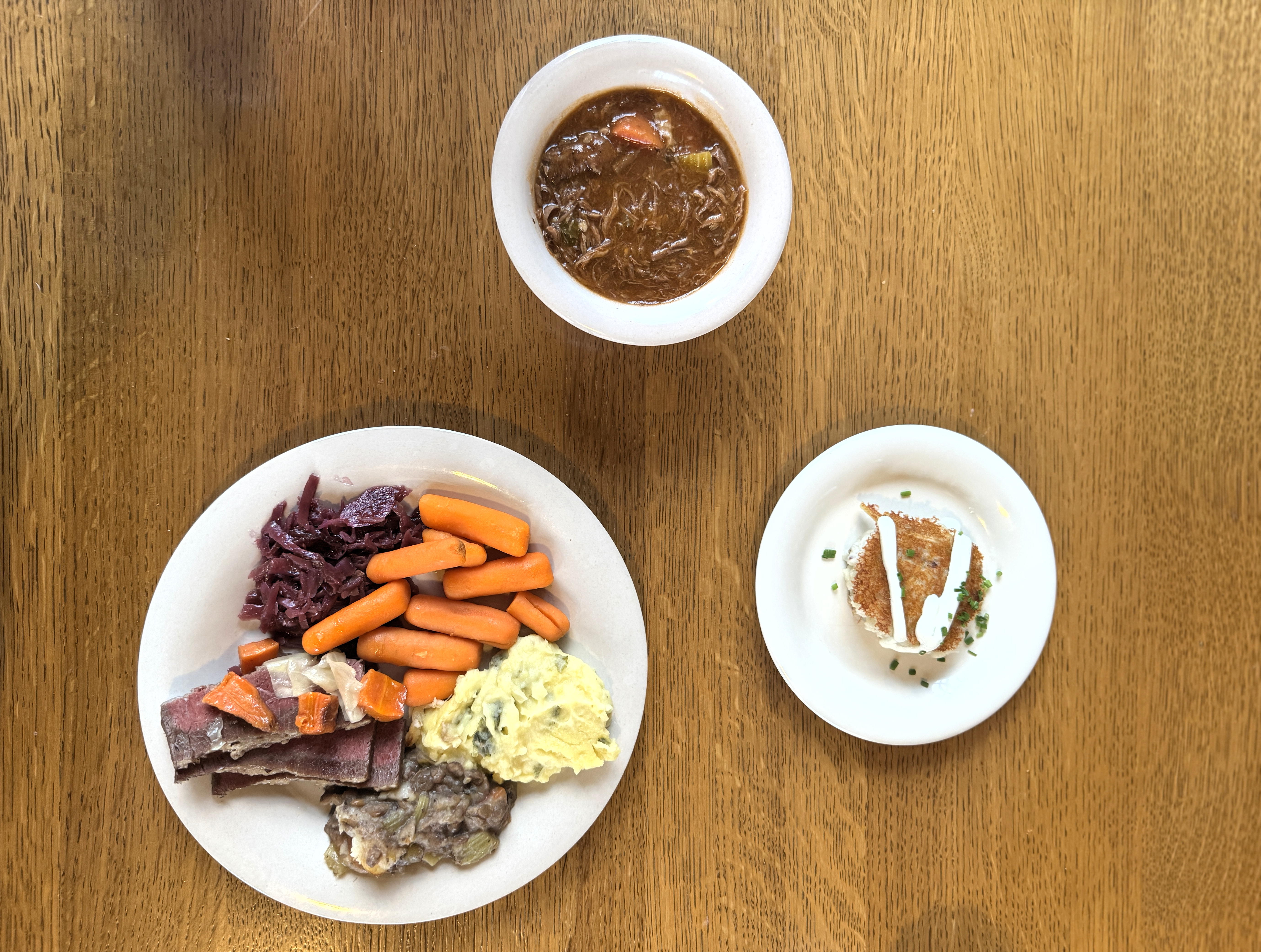 An overhead view of three plates of food on a wood pattern table top