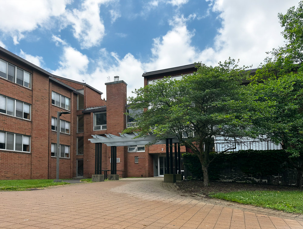 Brick low rise building with green tree and patio