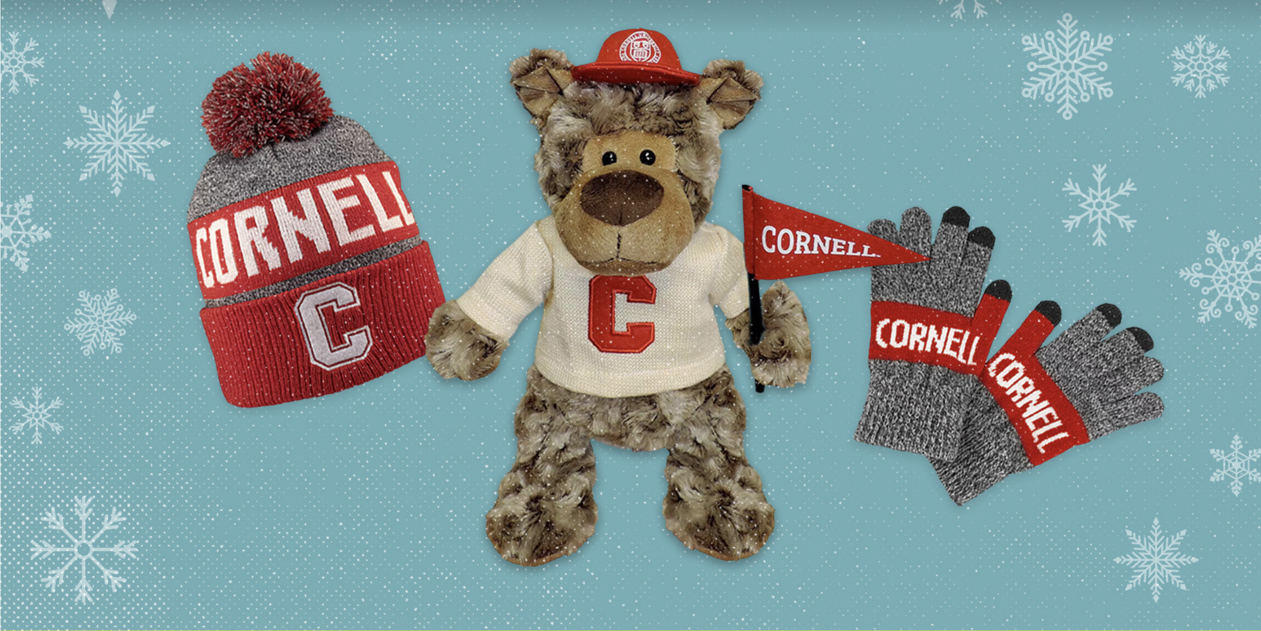 cornell Branded gifts of a hat, teddy bear, and gloves on a snowy blue background